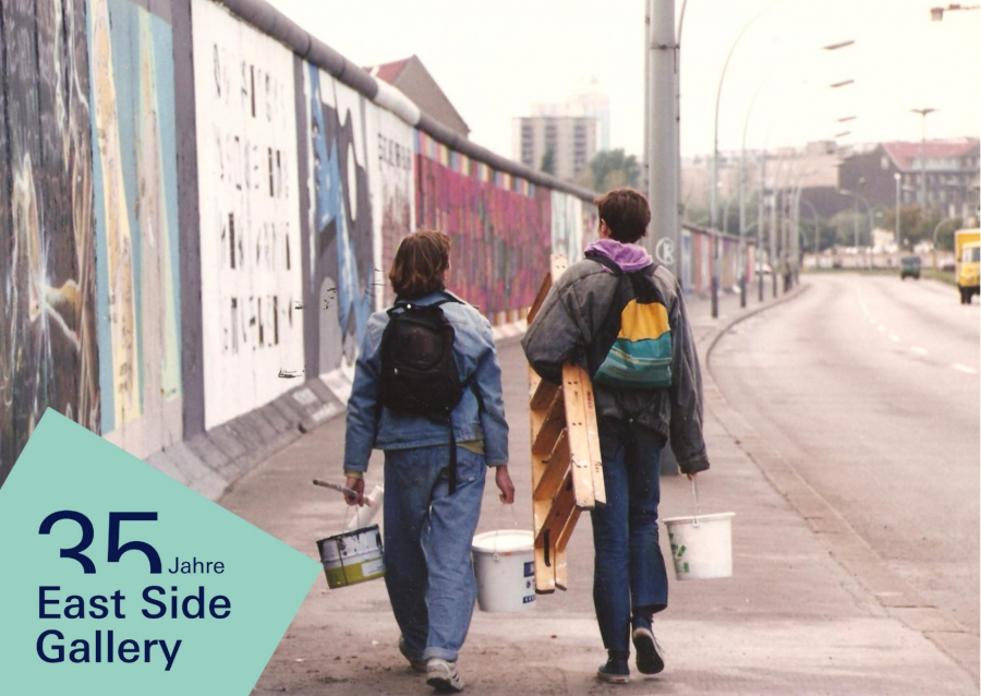 Personen mit Malwerkzeugen laufen entlang der East Side Gallery